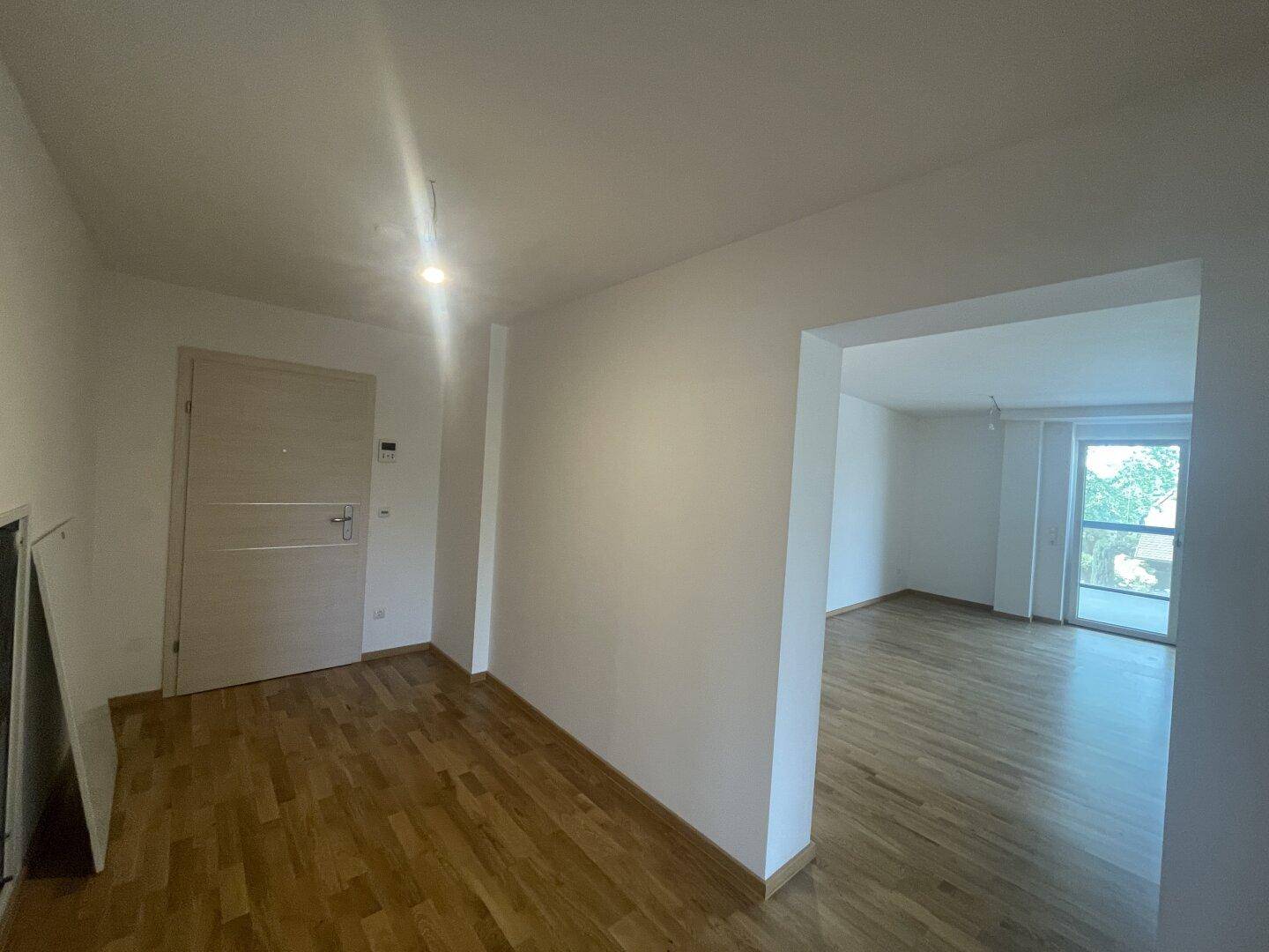 Heller Eingangsbereich mit Holzfußboden, der zu den weiteren Wohnbereichen führt.