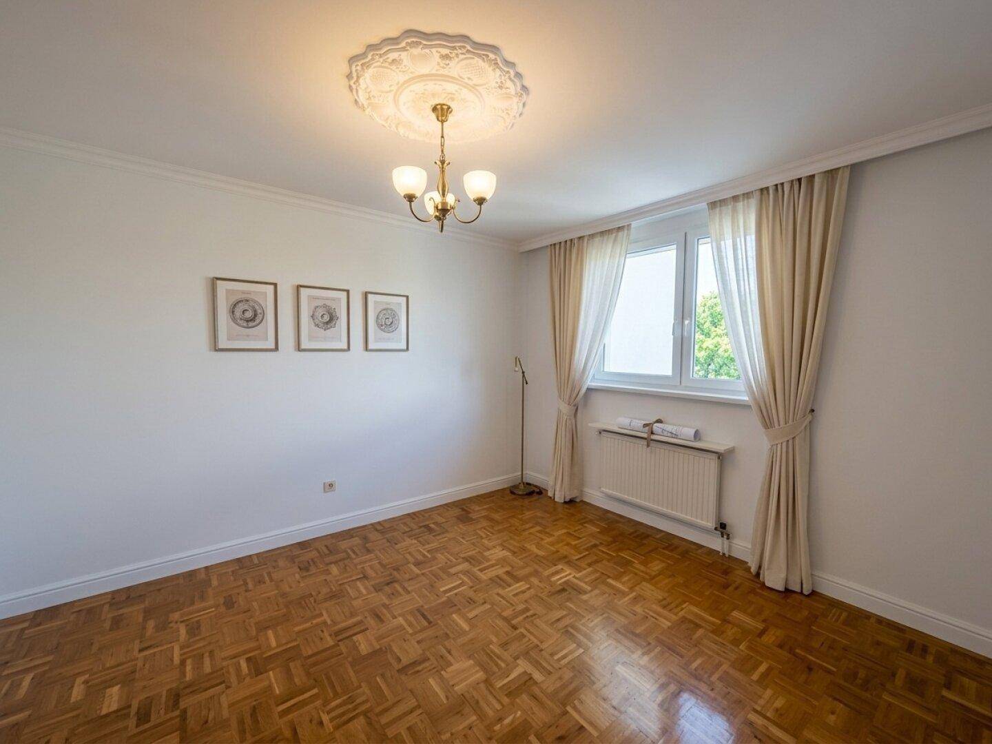 Geräumiges Zimmer mit Parkettboden, Stuckdecke und großem Fenster.