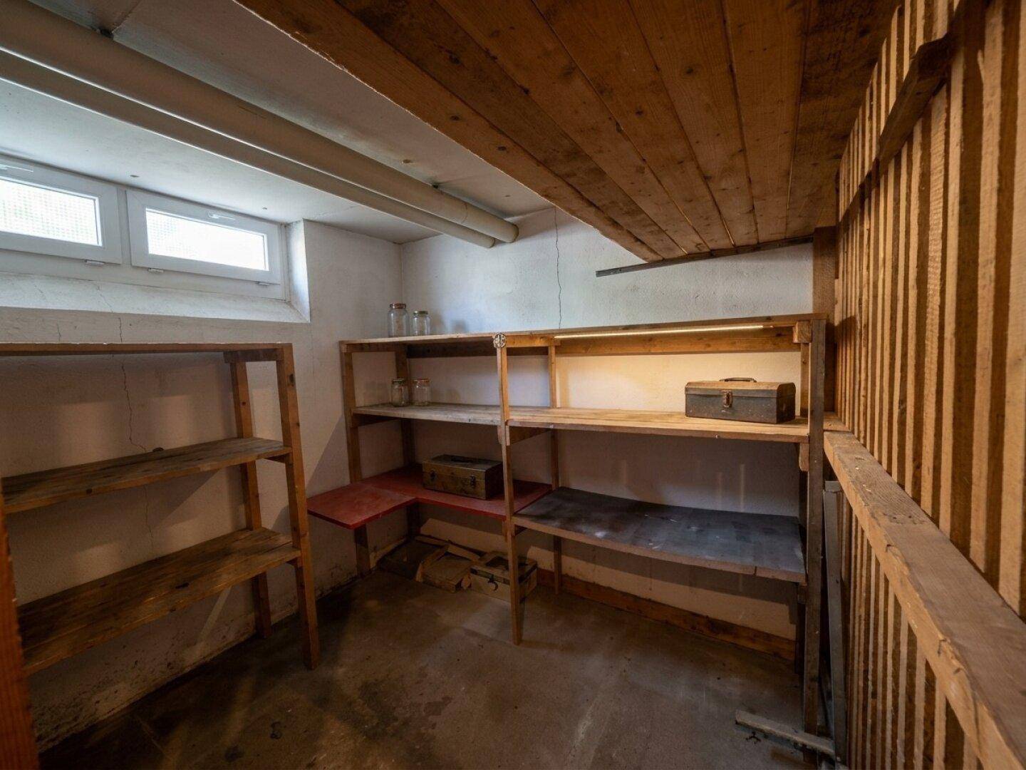 Kellerraum mit Holzregalen und kleinem Fenster für zusätzlichen Stauraum.
