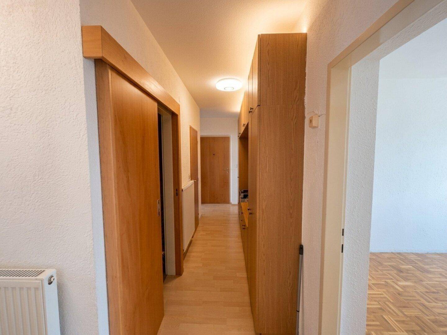 Heller Flur mit Holzschränken und Parkettboden.
