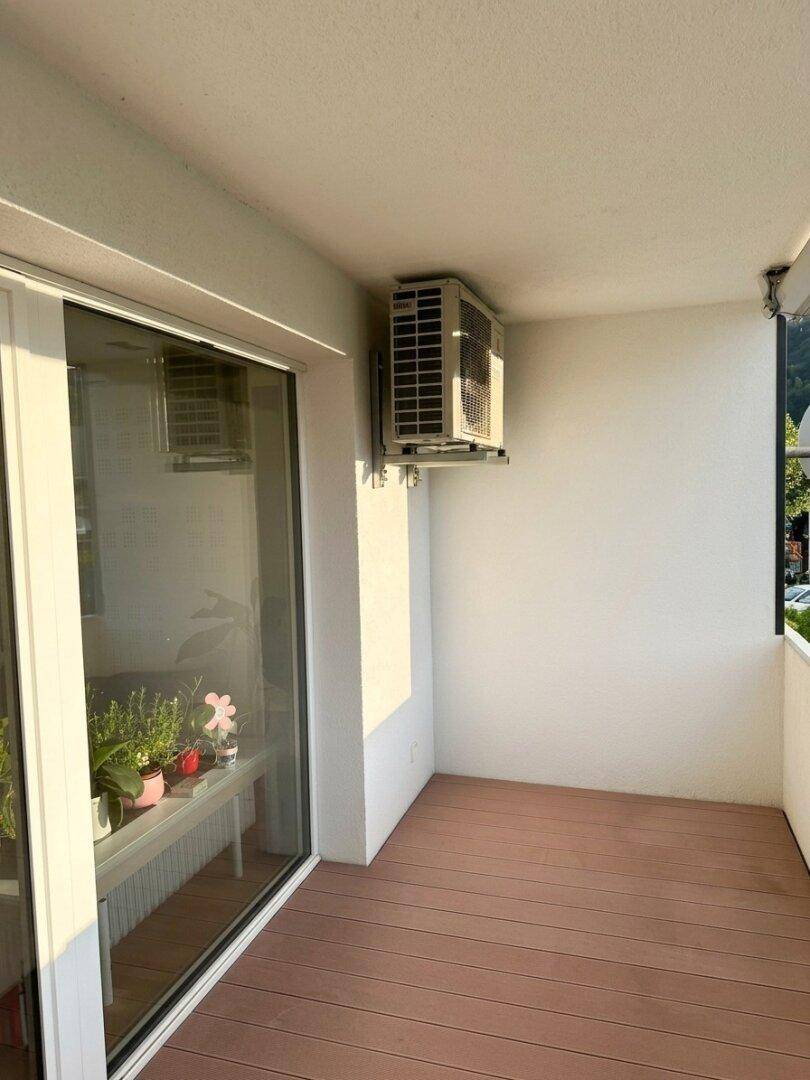 Kleiner Balkon mit Klimaanlage und Holzboden, ideal für frische Luft.