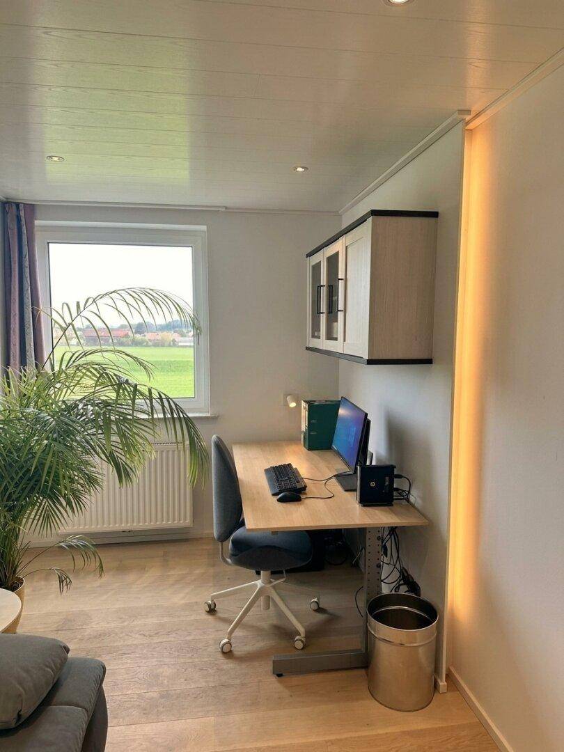 Helles Arbeitszimmer mit Schreibtisch, Bürostuhl und Blick ins Grüne.