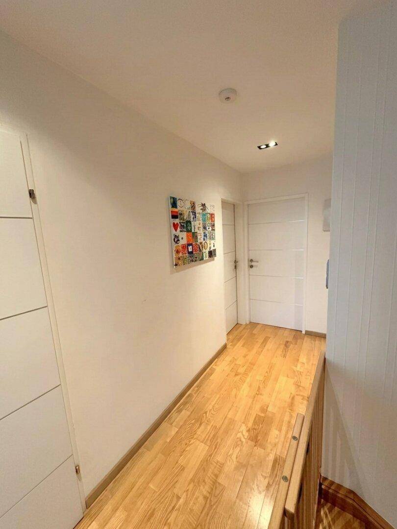 Heller Flur mit Holzboden und modernen weißen Türen.