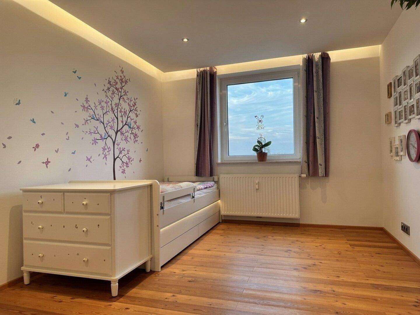 Kinderzimmer mit Einzelbett, Kommode und verspielter Wanddekoration.