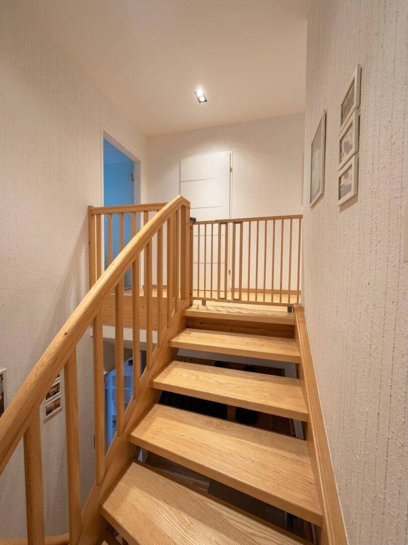 Helle Holztreppe mit Kinderschutzgitter und weiß gestrichenen Wänden.