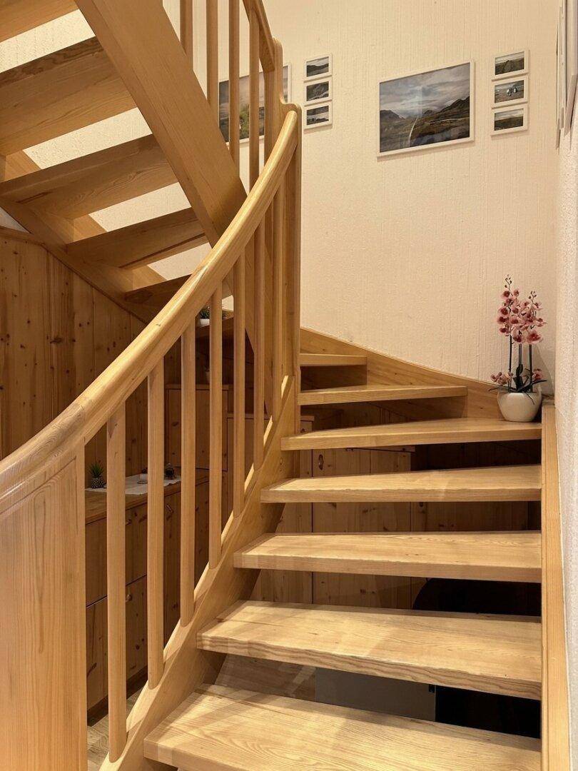 Massive Holztreppe mit Geländer und dekorativen Elementen an der Wand.