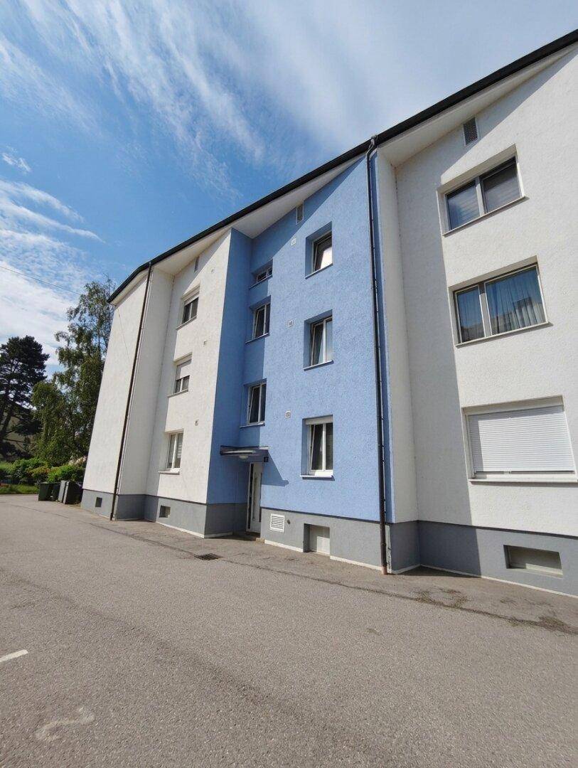 Fassade eines Mehrfamilienhauses mit weißem und blauem Anstrich unter blauem Himmel.