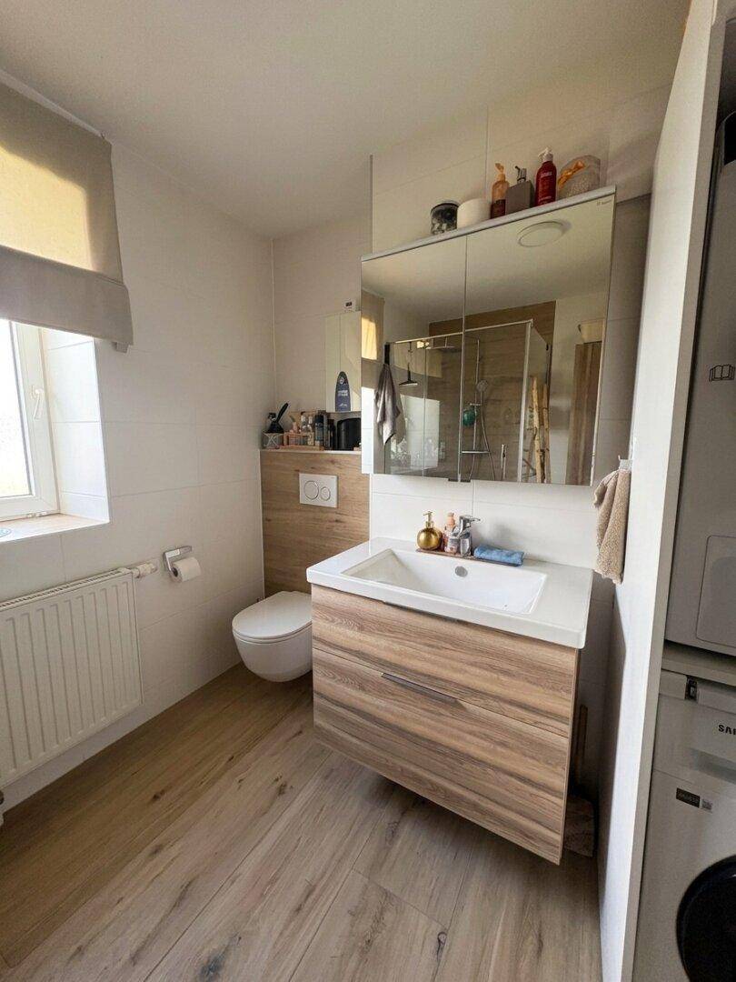 Helles Badezimmer mit modernem Waschtisch, wandhängendem WC und Fenster.