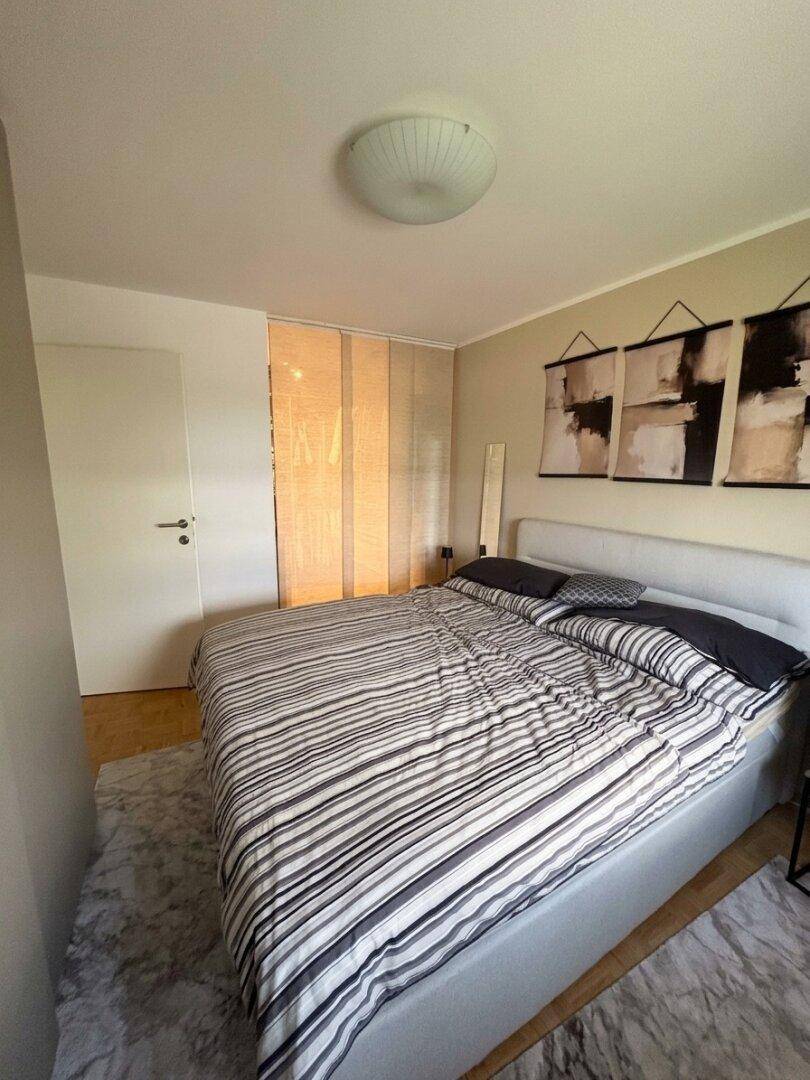 Gemütliches Schlafzimmer mit Doppelbett, Teppich und heller Wandgestaltung.