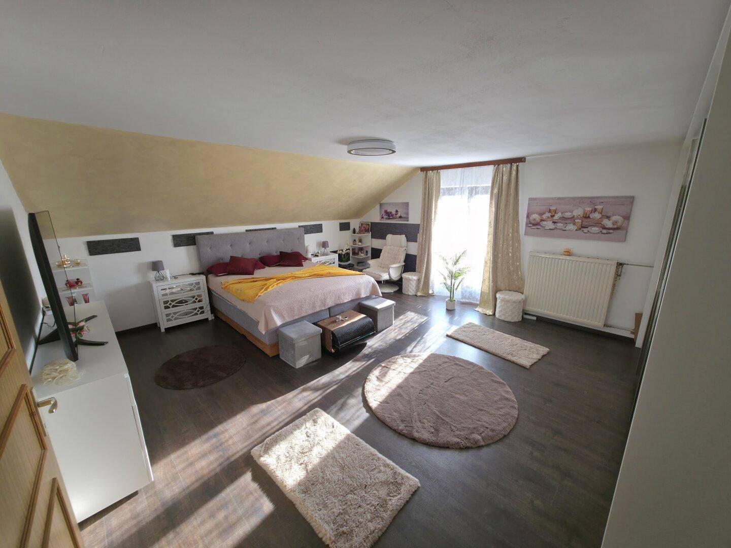 Helles Schlafzimmer im Dachgeschoss mit großem Fenster, Doppelbett und modernem Dekor.