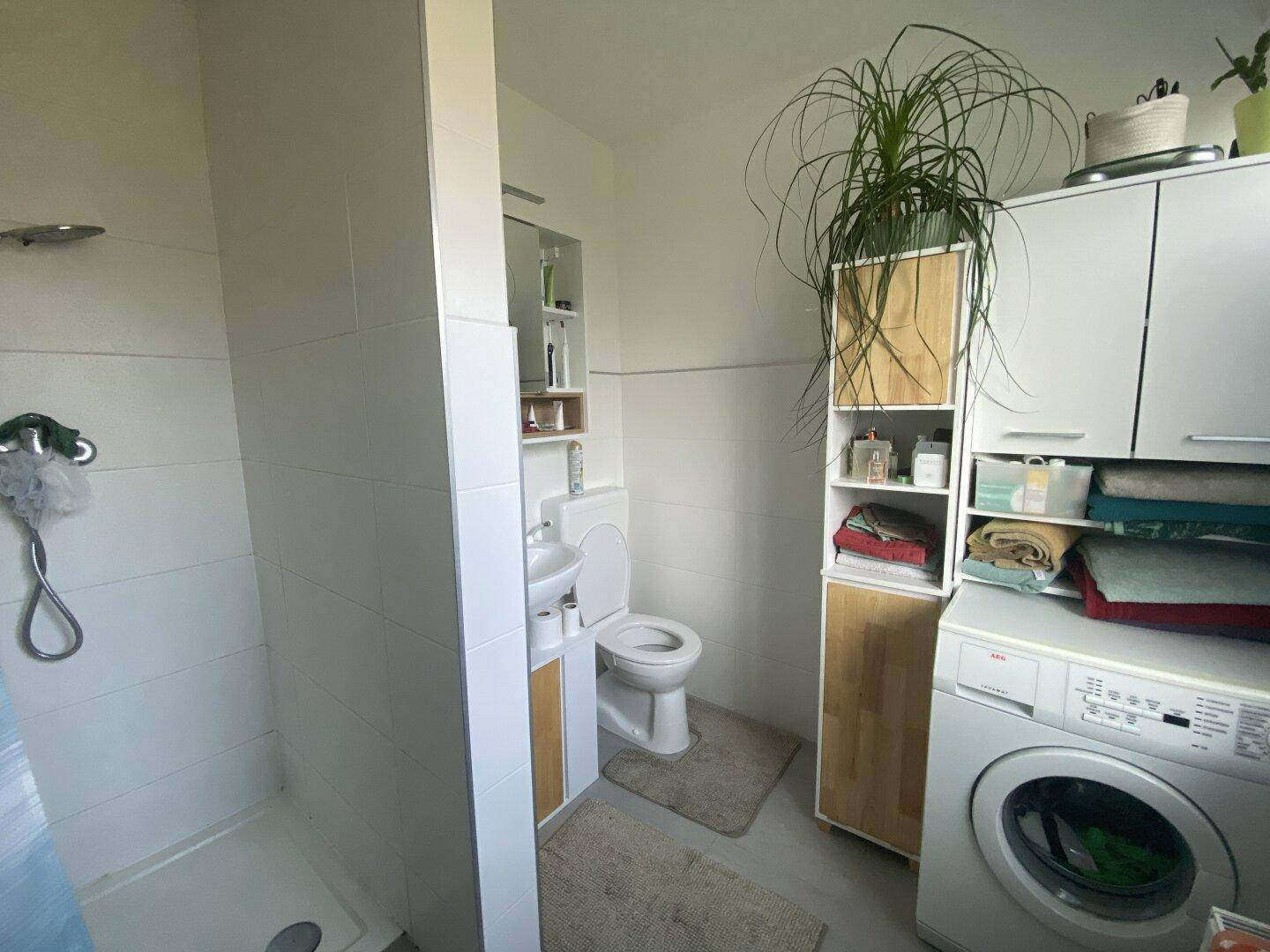 Modernes Badezimmer mit begehbarer Dusche, WC, Waschbecken und Waschmaschine.