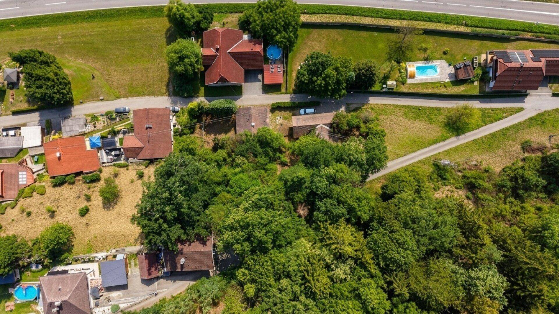 Luftaufnahme eines Wohngebiets mit Häusern, Gärten und einem Swimmingpool in der Nachbarschaft.