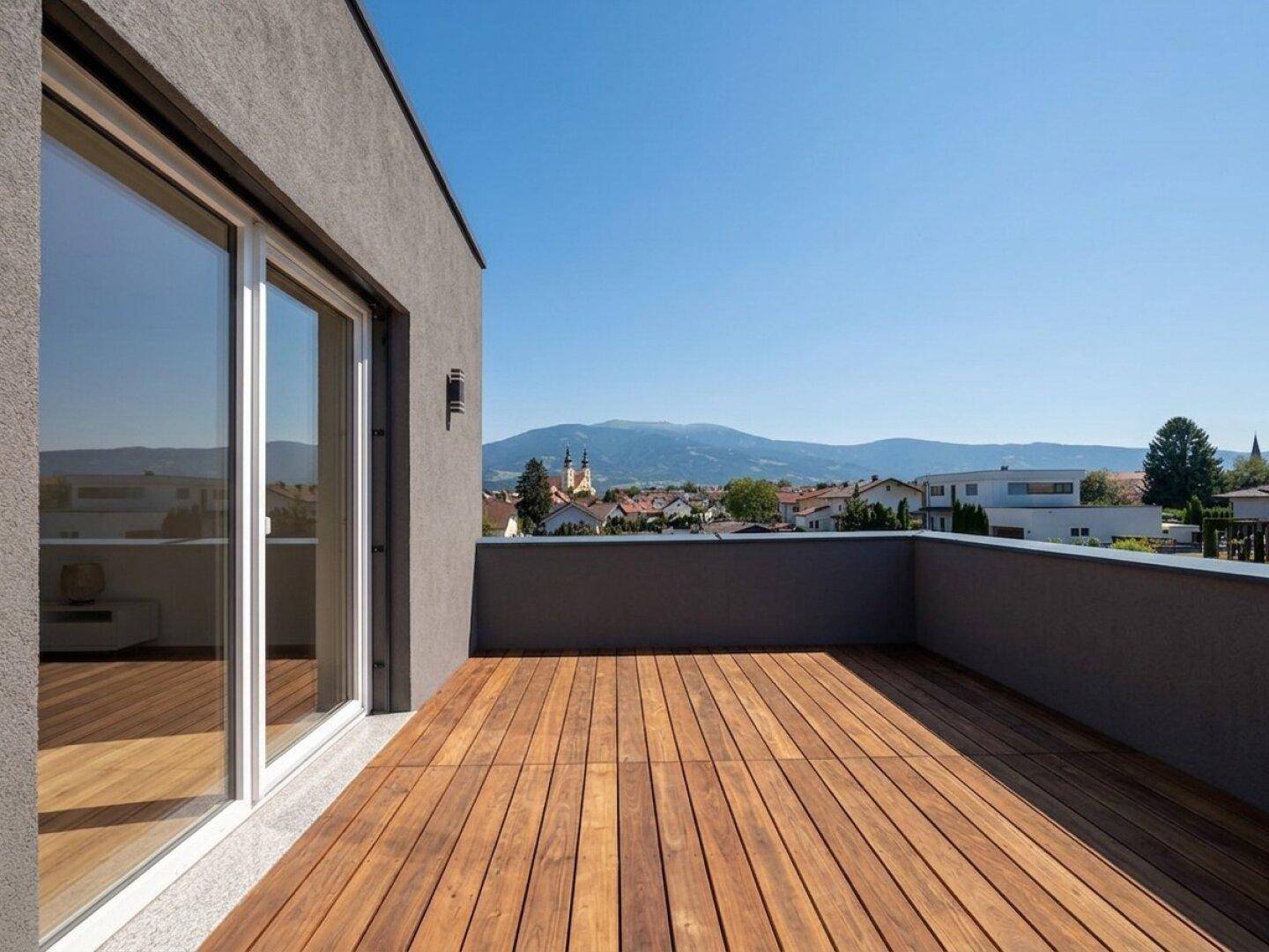 Geräumiger Balkon mit Holzboden und weitem Blick auf die Umgebung und die Berge.