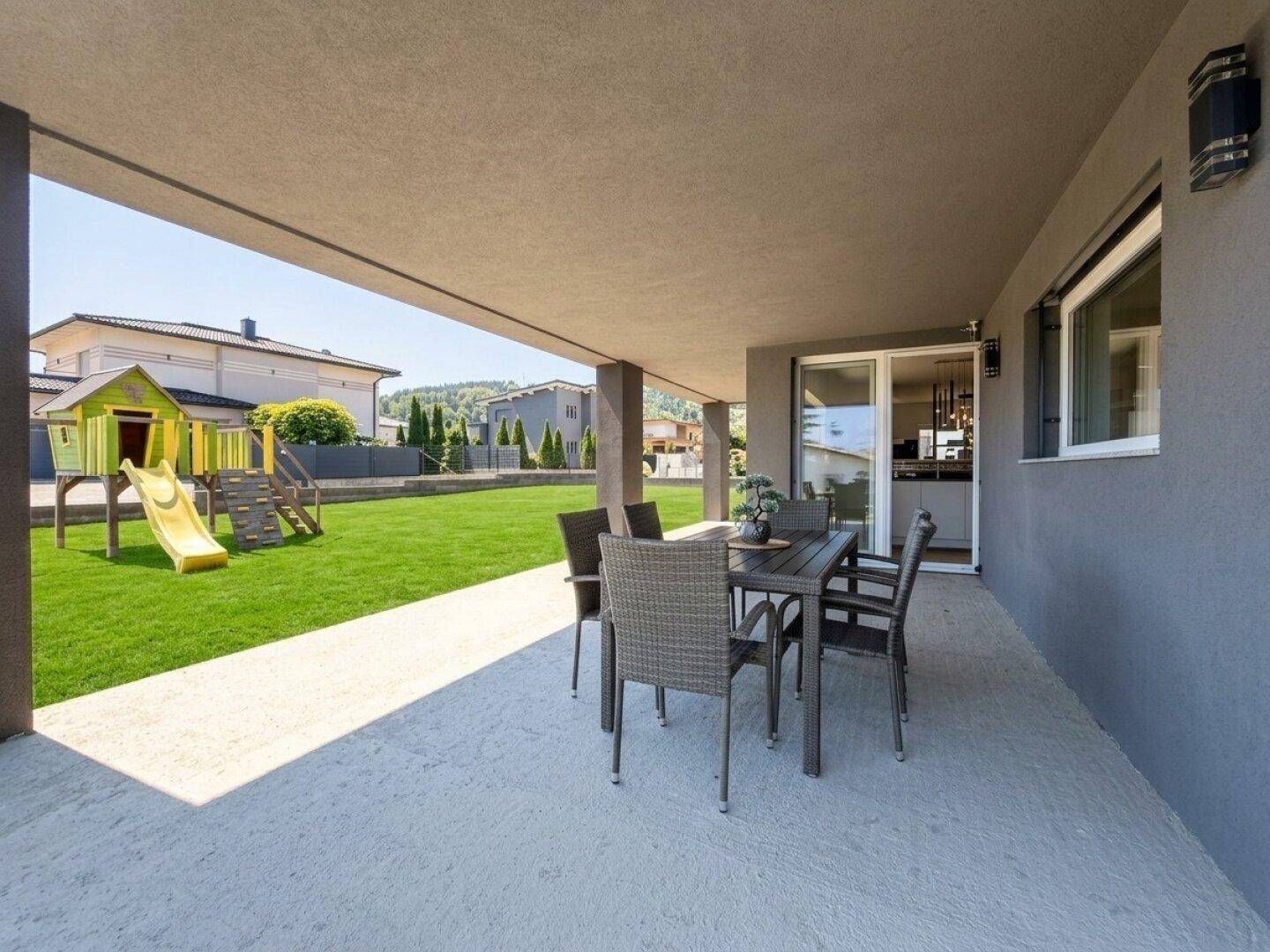 Überdachte Terrasse mit Essbereich und angrenzendem Garten mit Spielplatz für Kinder.