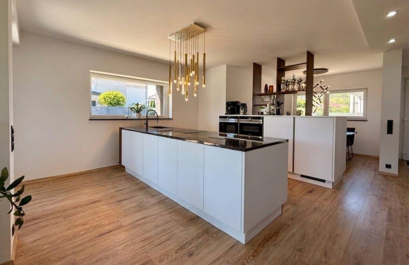 Geräumige, moderne Küche mit großer Kochinsel und integriertem Barbereich für geselliges Beisammensein.