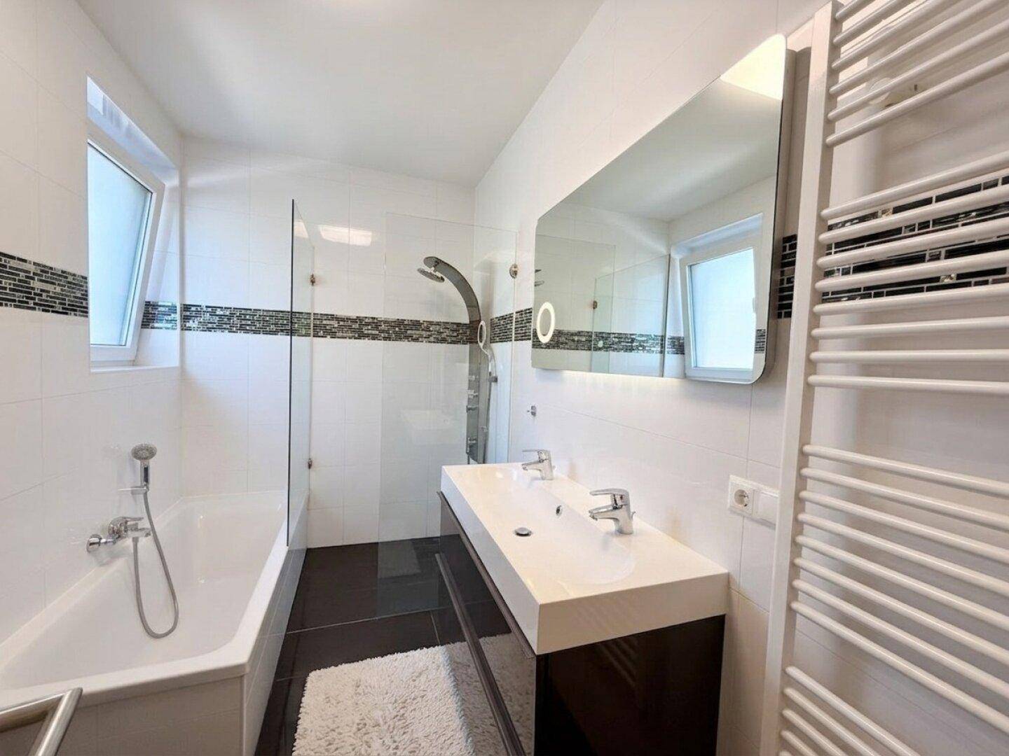Modernes Badezimmer mit Badewanne, Dusche, Doppelwaschbecken und beheiztem Handtuchhalter.