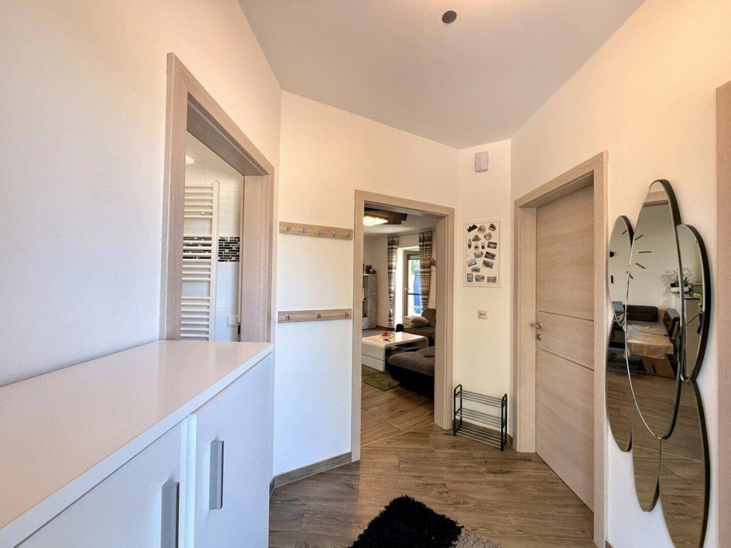 Heller Flur mit Holzoptikboden, Garderobe und Zugang zu verschiedenen Räumen.