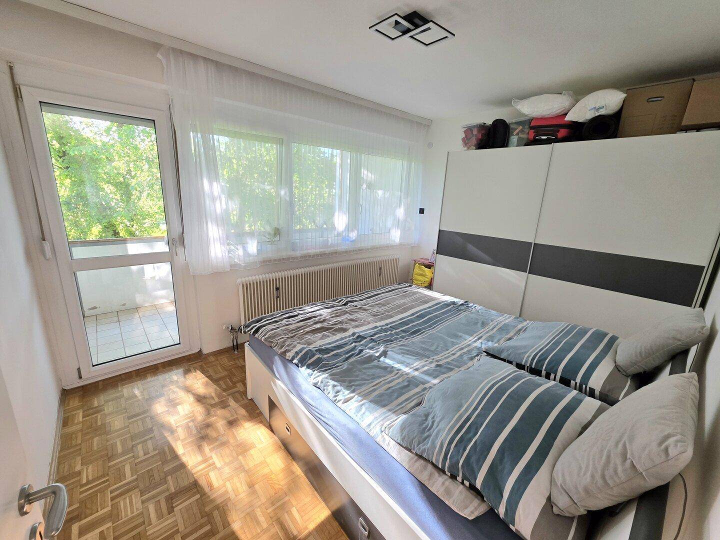 Schlafzimmer mit Doppelbett, großem Kleiderschrank und Zugang zum Balkon.
