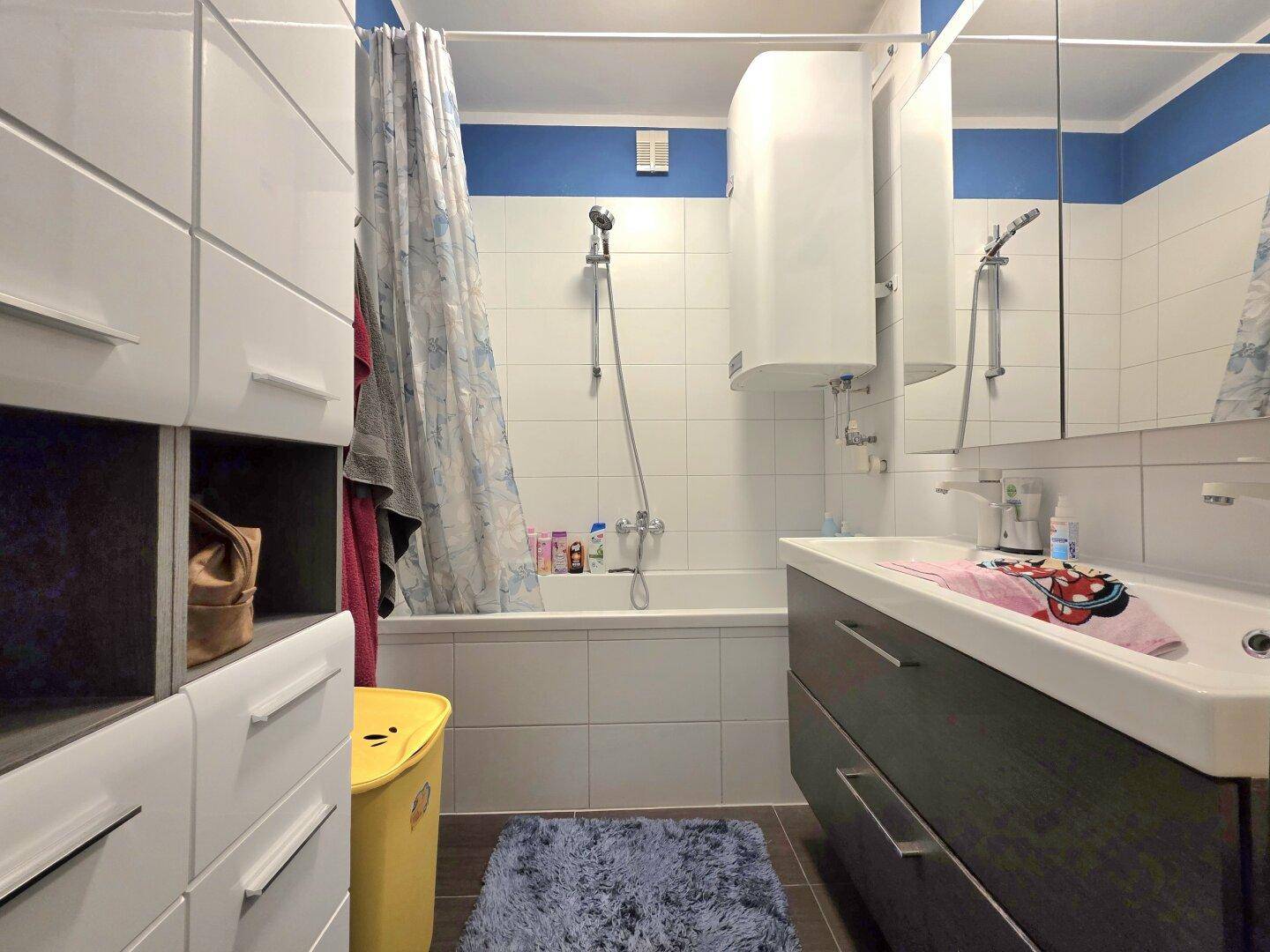 Badezimmer mit Badewanne, Duschvorhang und modernem Waschtischunterschrank.