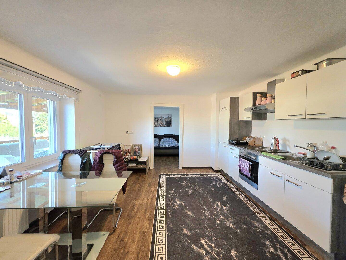 Offene Küche mit Essbereich, weißen Schränken und Holzboden.