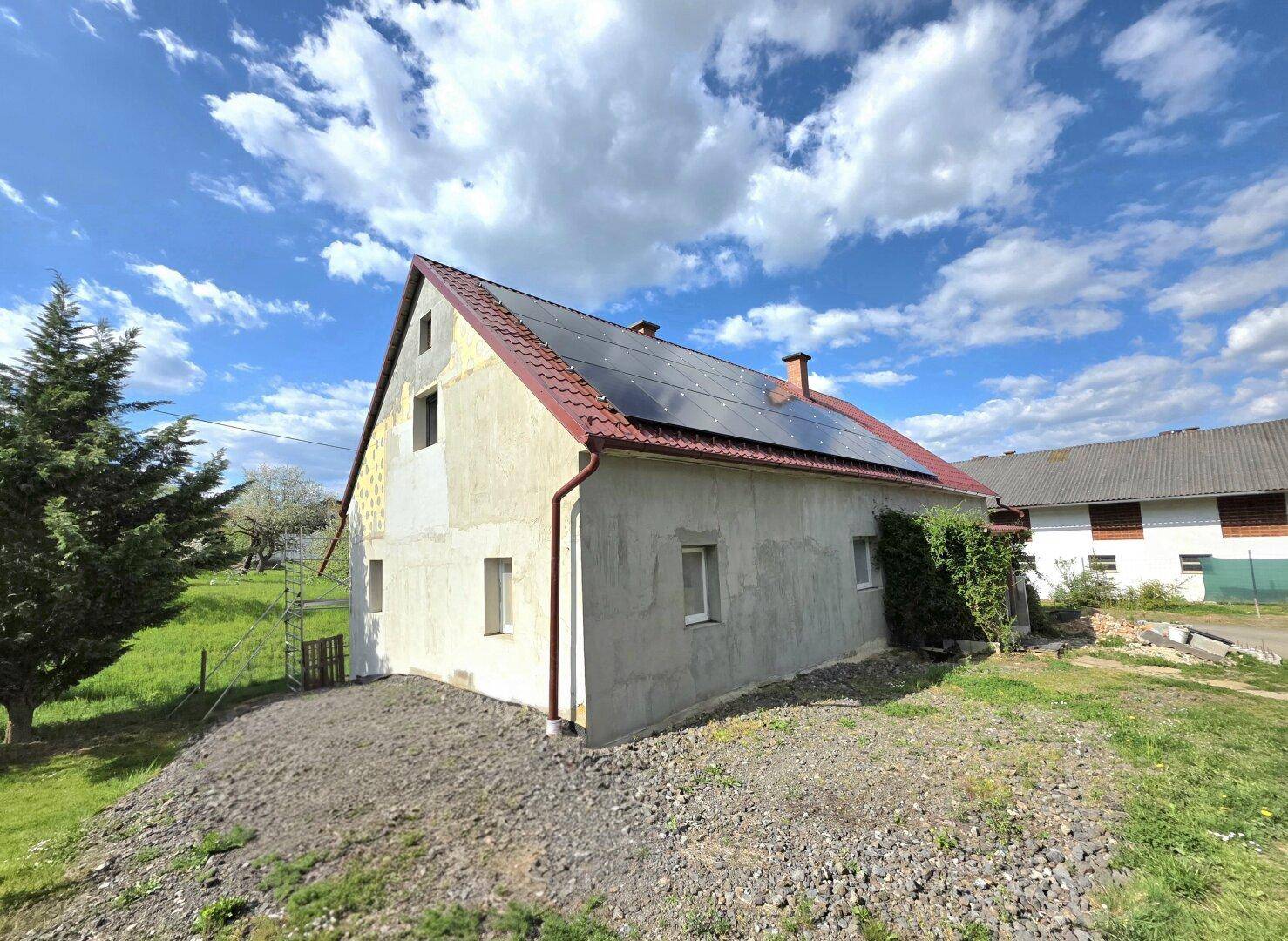 Rückansicht des Hauses mit installierter Photovoltaikanlage und grünem Gartenbereich.