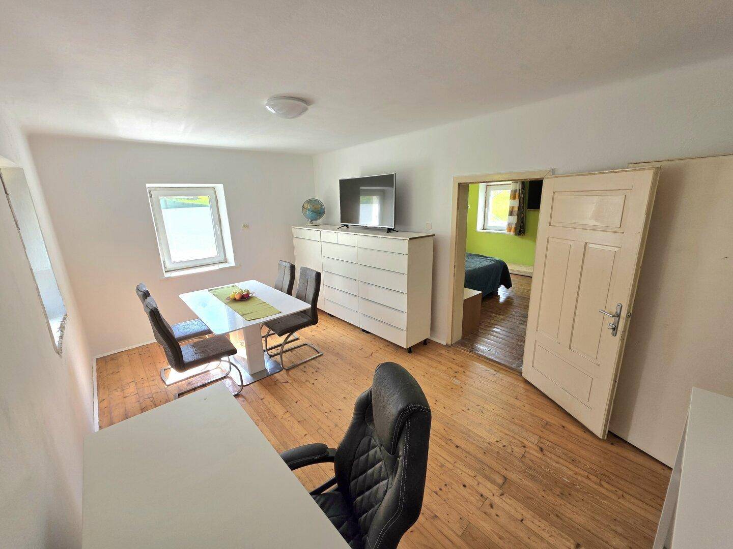 Heller Essbereich mit modernem Tisch und Stühlen, angrenzend an ein weiteres Zimmer.