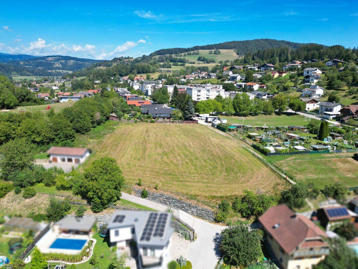 Weitläufiges Grundstück in einer Wohngegend mit Blick auf umliegende Häuser und grüne Hügel.