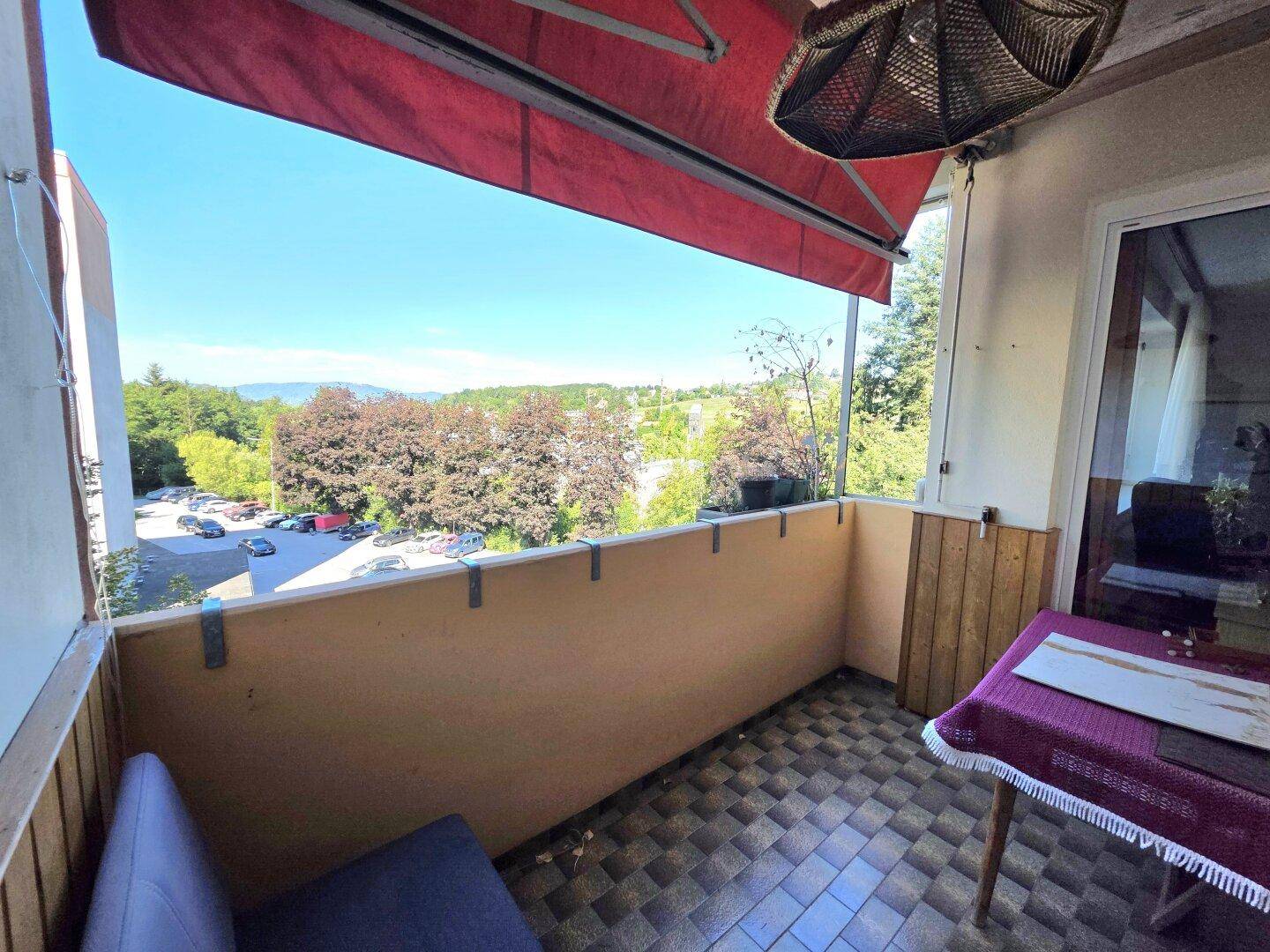 Balkon mit Markise und Blick auf die Umgebung, ausgestattet mit Fliesenboden.