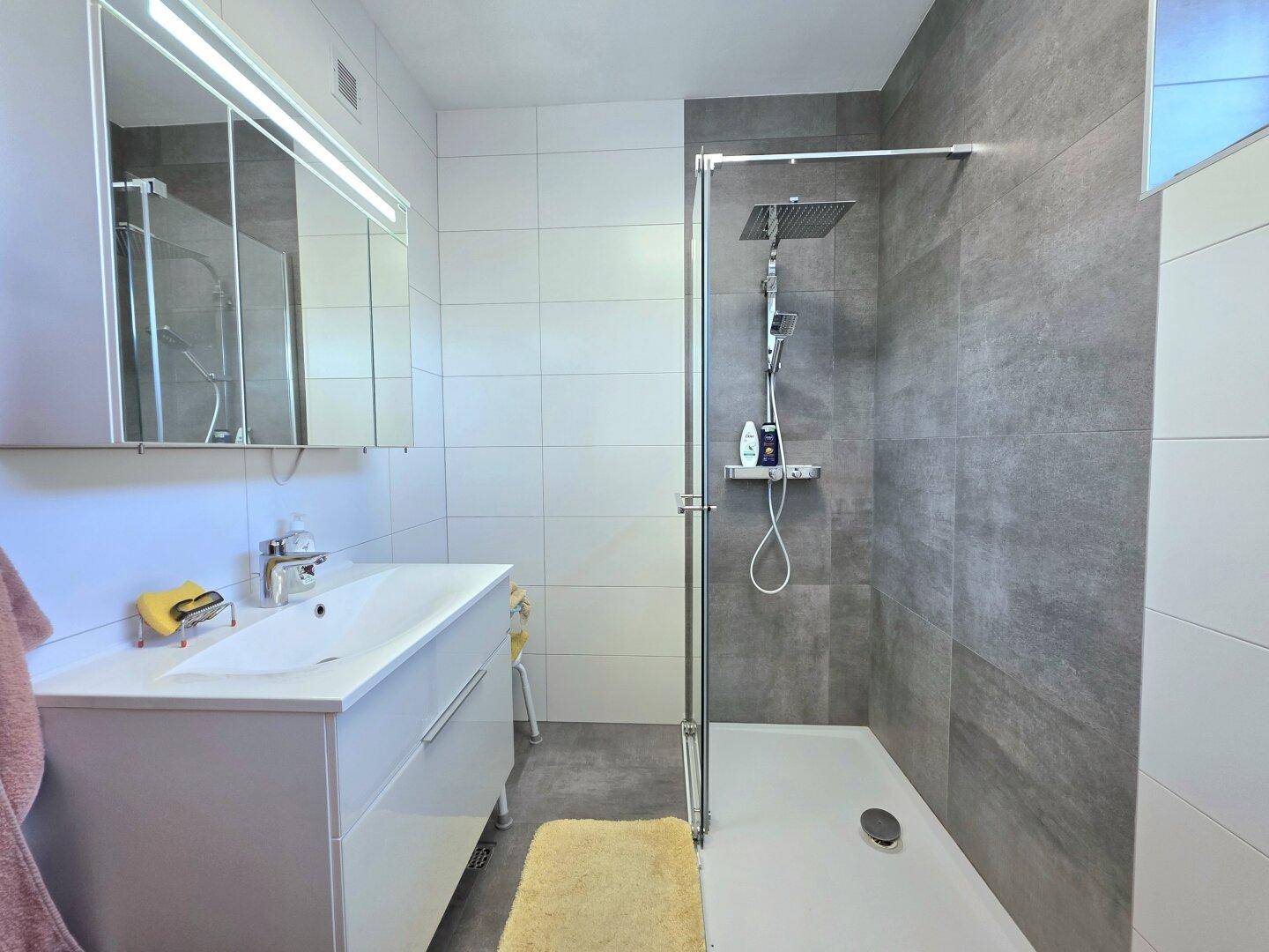 Modernes Badezimmer mit begehbarer Dusche, großformatigen Fliesen und Einzelwaschbecken.