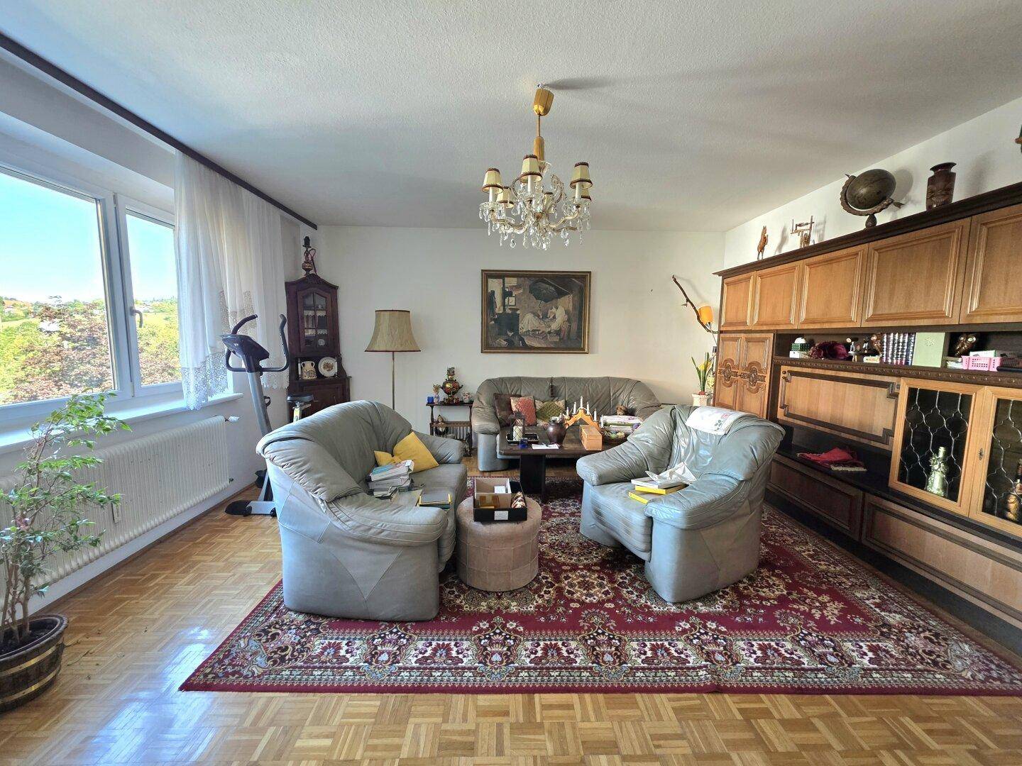 Geräumiges Wohnzimmer mit Parkettboden, traditionellen Möbeln und Kronleuchter.