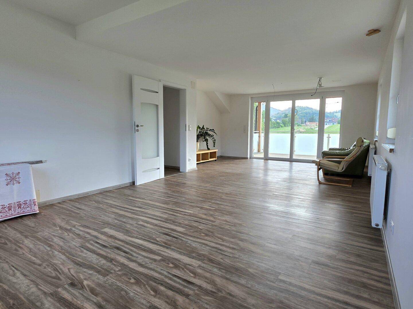 Großer Wohnbereich mit Laminatboden, Balkonzugang und weitem Ausblick.