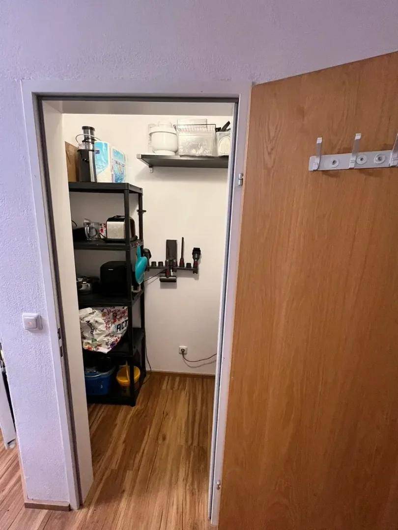 Praktischer Abstellraum mit Regalen und Holzboden, ideal für Vorräte und Haushaltsgeräte.