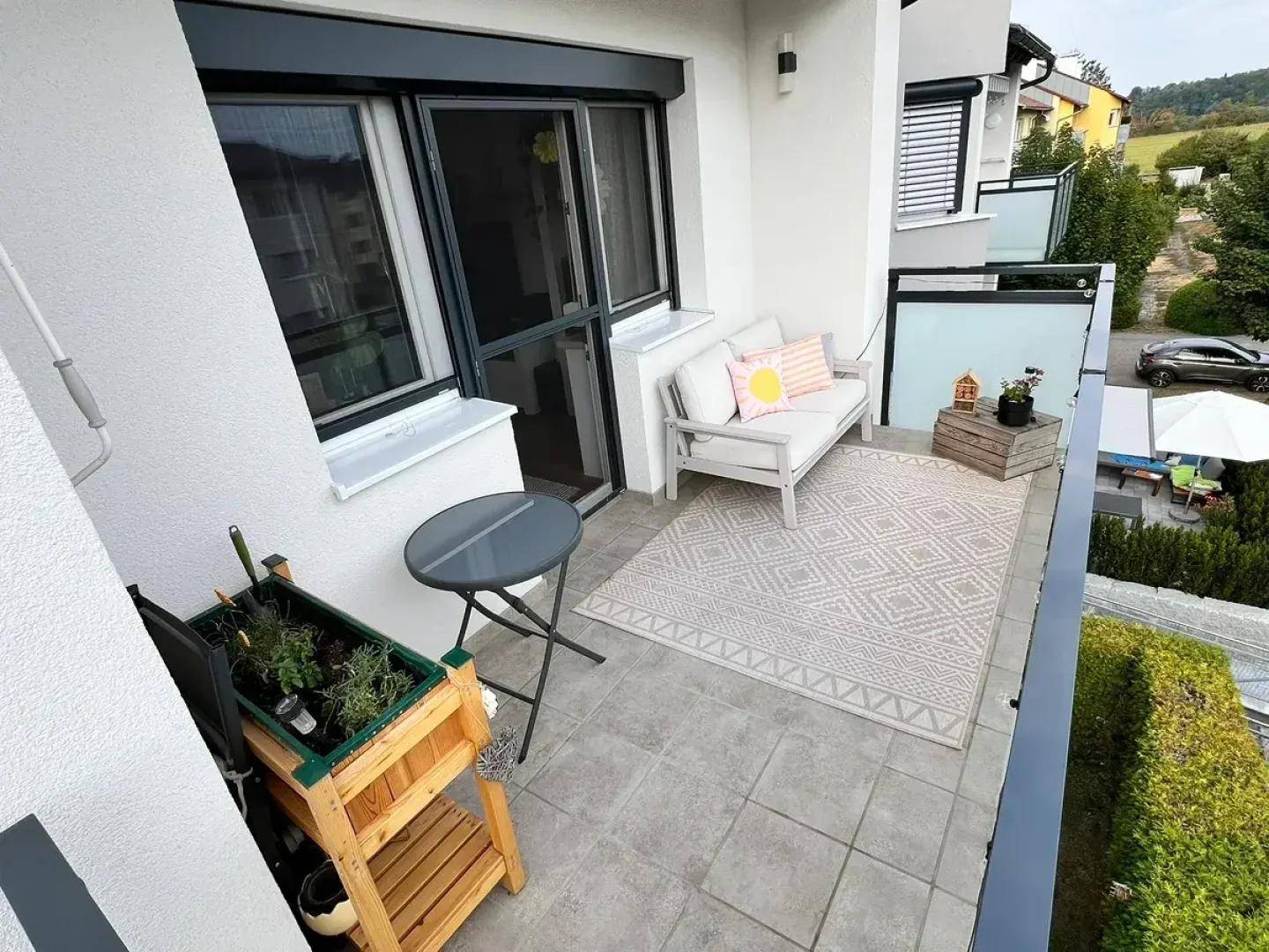 Geräumiger Balkon mit Sitzgelegenheiten und Teppich, bietet einen angenehmen Außenbereich.