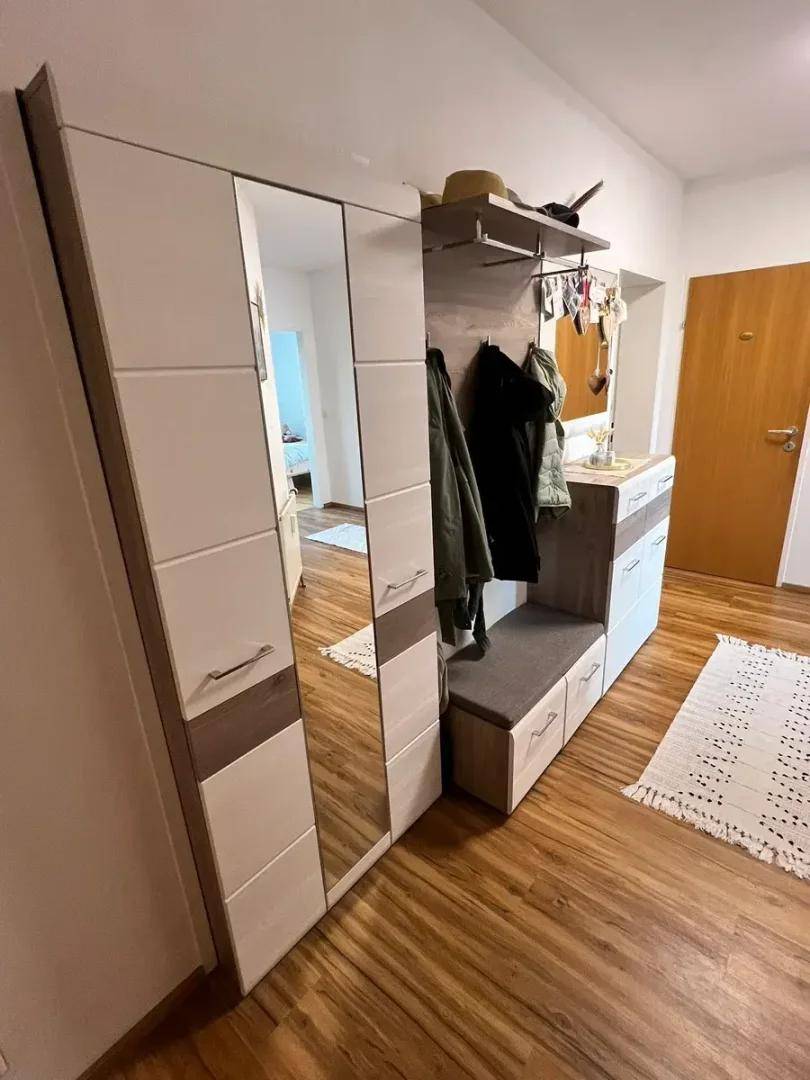 Eingangsbereich mit Garderobe, Spiegel und Holzboden, einladend gestaltet.