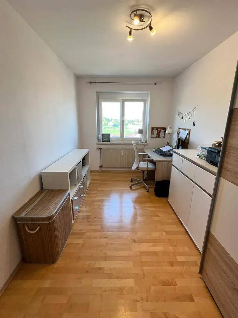 Helles Zimmer mit Holzboden, Schreibtisch und Stauraum, vielseitig nutzbar.