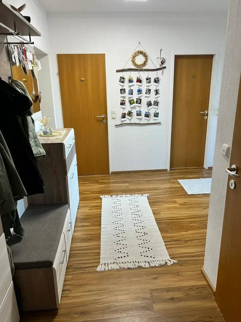 Heller Flur mit Garderobe und Holzboden, der zu den verschiedenen Räumen führt.