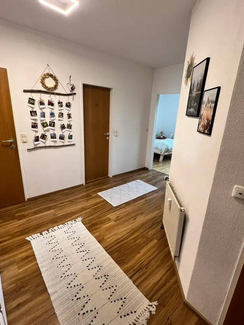 Heller Flur mit Holzboden und modernen Dekorationen, der zu weiteren Räumen führt.