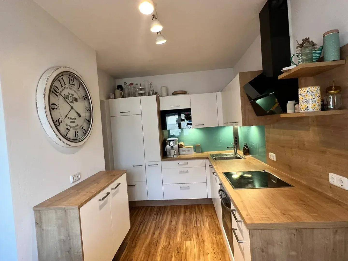 Moderne Küche mit weißen Schränken, Holz-Arbeitsplatten und integrierten Geräten.