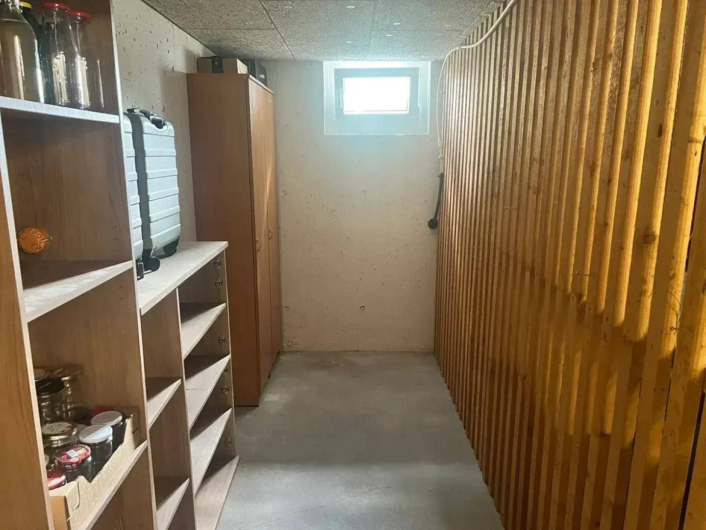 Geräumiger Kellerraum mit Regalen und kleinem Fenster, bietet viel Stauraum.
