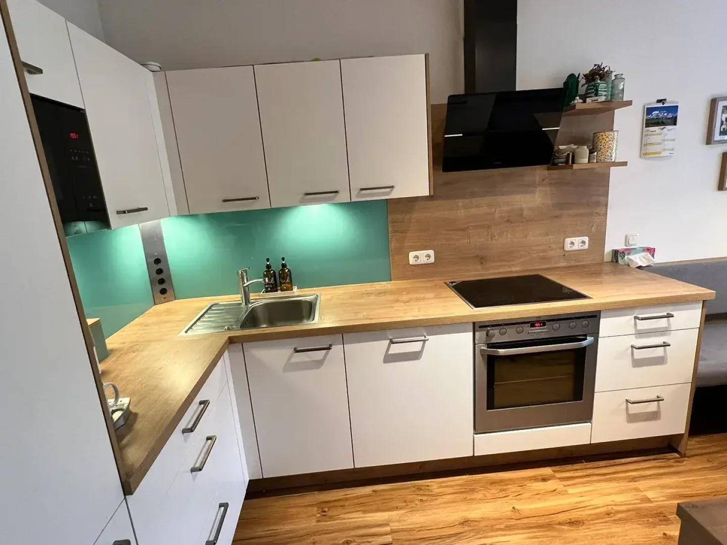 Moderne Küche mit weißen Schränken, Holz-Arbeitsplatten und integrierten Geräten.