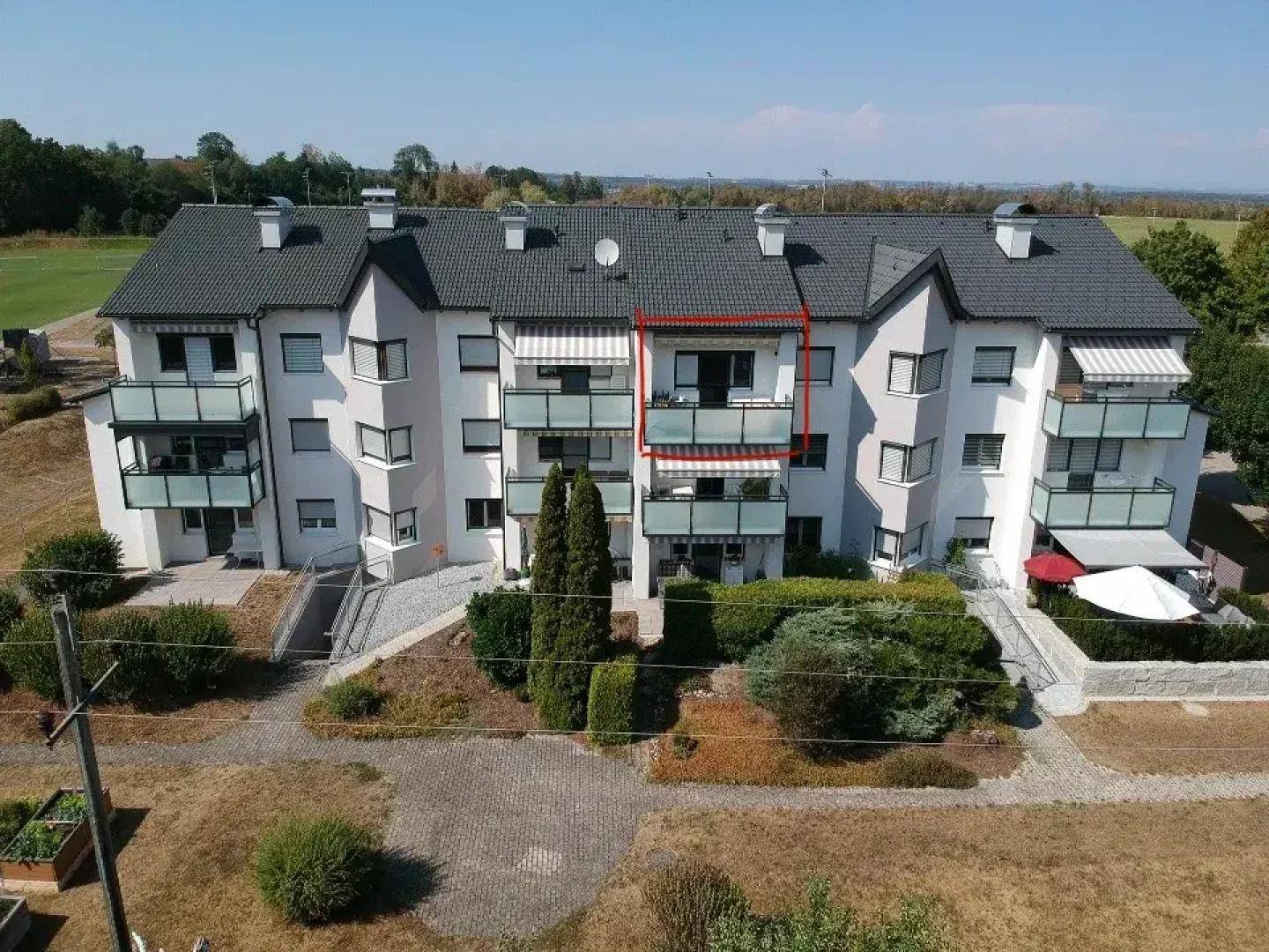 Luftaufnahme eines Mehrfamilienhauses mit Balkonen und gepflegter Außenanlage.