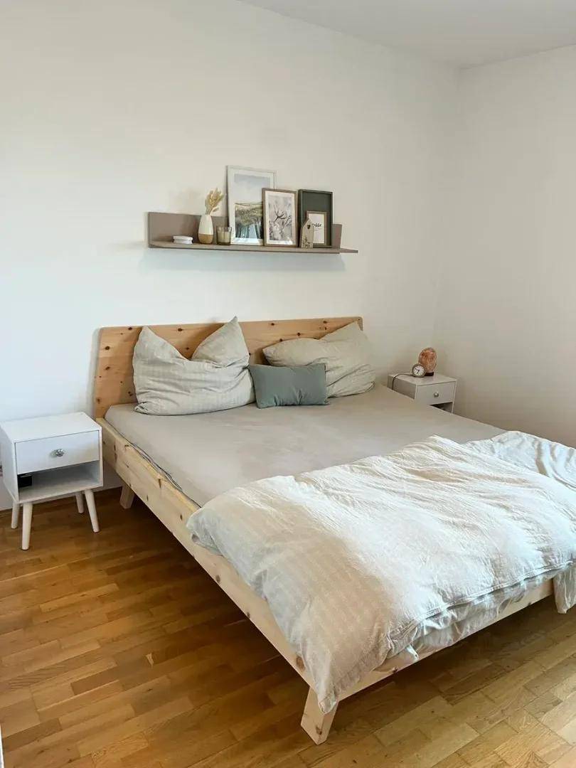 Helles Schlafzimmer mit Holzbett, Nachttischen und Wandregal, modern eingerichtet.