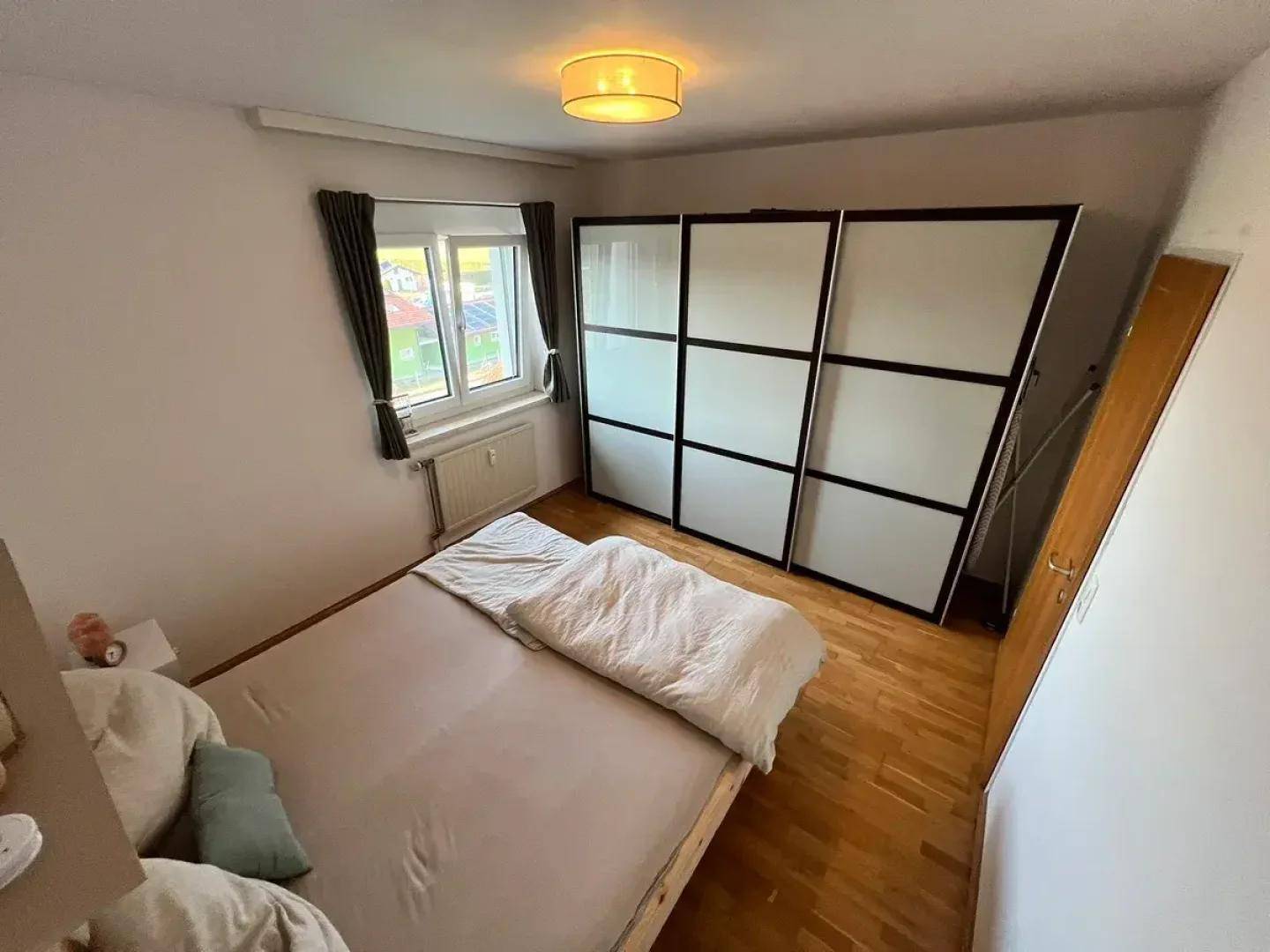 Schlafzimmer mit Holzboden und großem Kleiderschrank, bietet eine ruhige Atmosphäre.