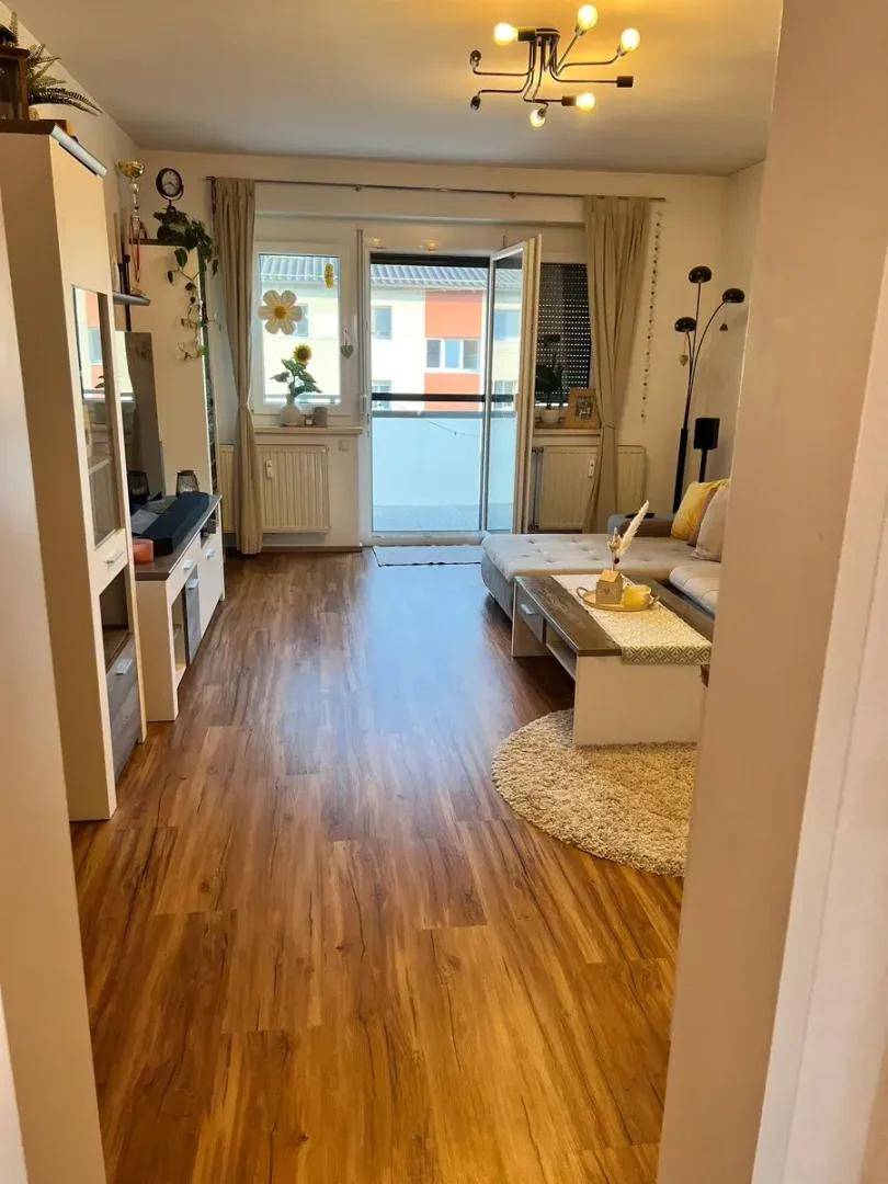 Gemütliches Wohnzimmer mit Sofa, Couchtisch und direktem Zugang zu einem Balkon.