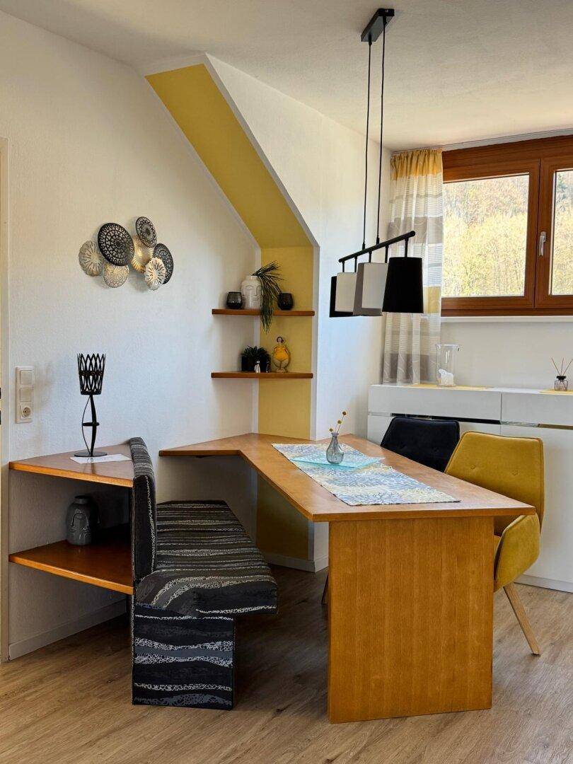 Heller Essbereich mit Holztisch, eingebauter Sitzbank und dekorativen Wandregalen.