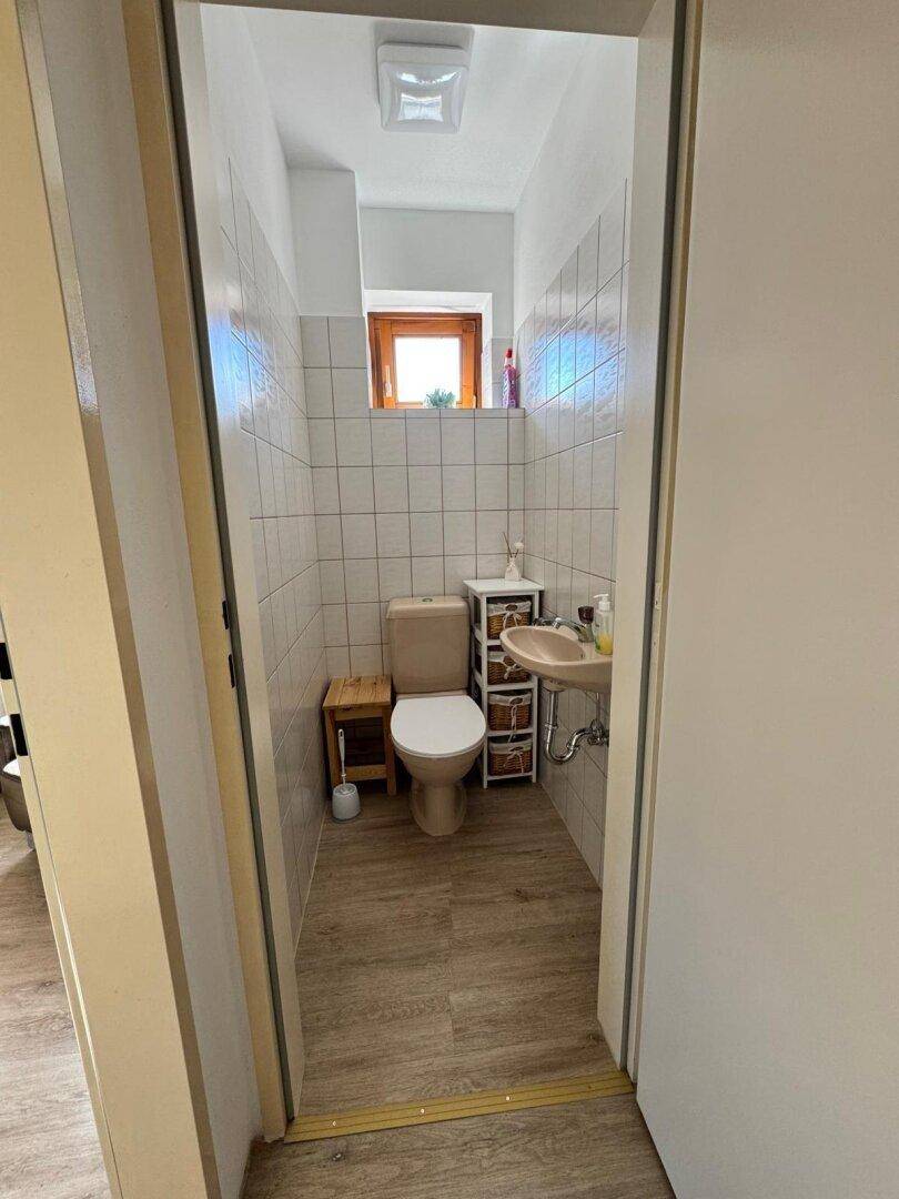 Kleines Gäste-WC mit Fenster, Toilette und Handwaschbecken.
