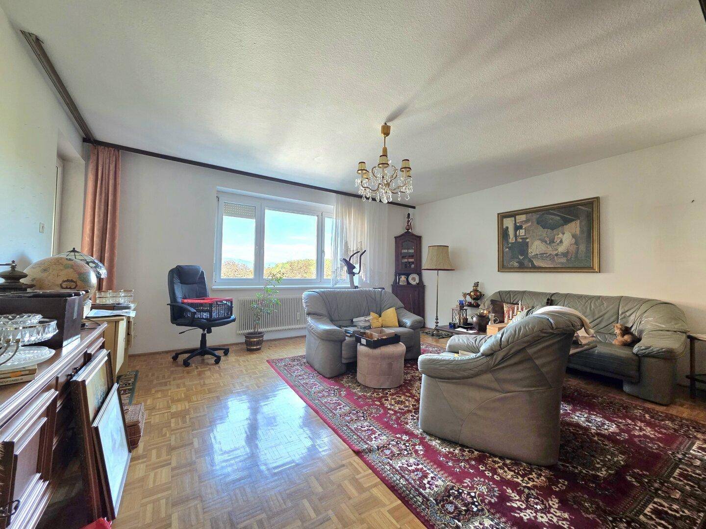 Helles Wohnzimmer mit Parkettboden, bequemen Sitzmöbeln und weitem Ausblick.