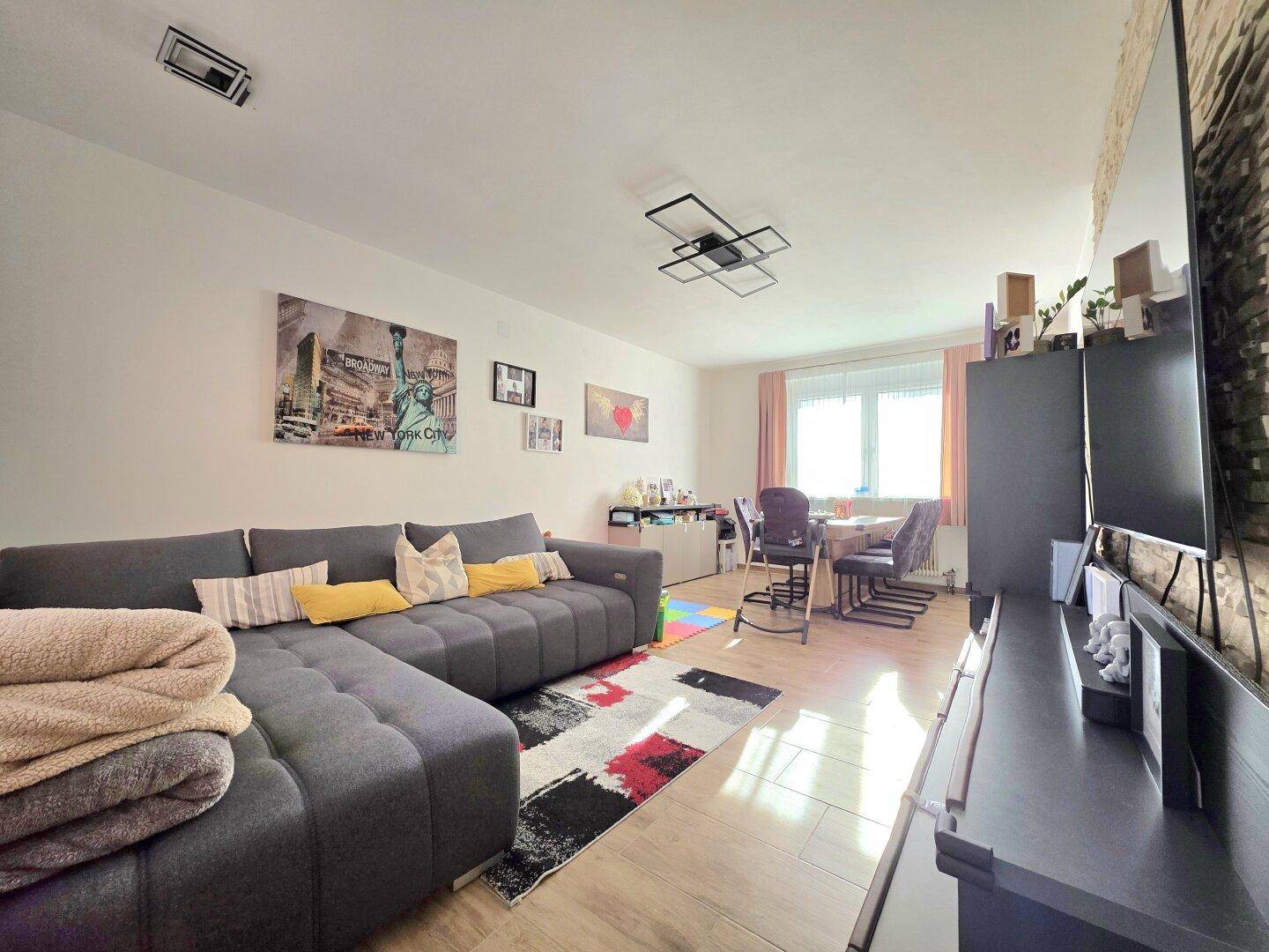 Geräumiger Wohn-Essbereich mit großem Sofa, Esstisch und hellem Bodenbelag.