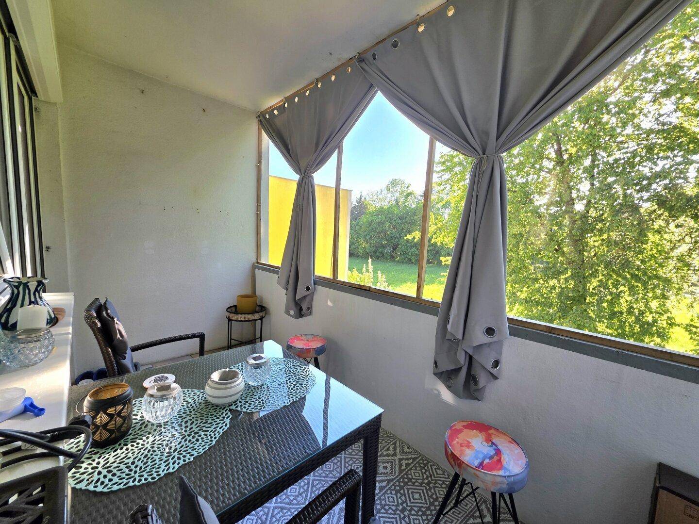 Gemütlicher Balkon mit Esstisch, Stühlen und Blick ins Grüne.
