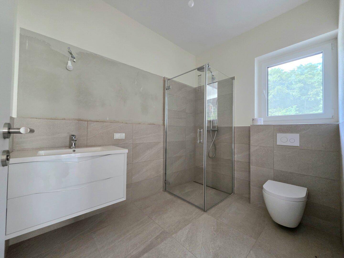 Modernes Badezimmer mit begehbarer Dusche, Waschtisch und wandhängendem WC, hell gefliest.